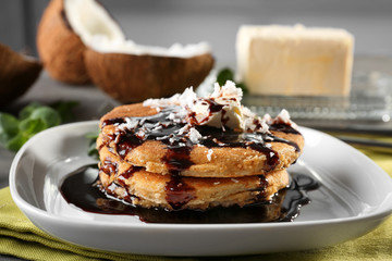 Tasty homemade coconut pancakes with chocolate sauce on plate