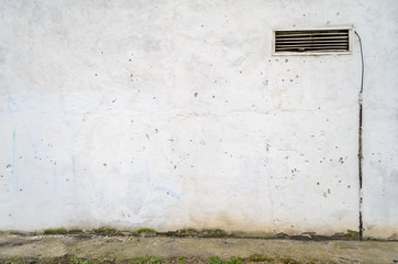 Old ventilation grille with bars on a grungy building, white wall