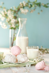 Good morning! Russian marshmallow with bottle and glass of milk on wooden background. Spring composition. Sweet breakfast in pastel colors on green napkin. Healthy food. Rustic style.