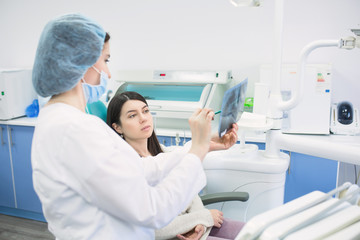 Obraz premium Doctor talking with patient and showing a radiograph in stomatology clinic