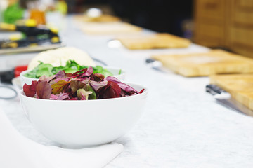 Fresh leaves of chard-salad in a white large bowl on a table in the kitchen. 