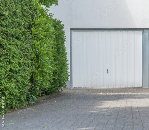"Weißes Garagentor mit weißer Fassade" Stockfotos und lizenzfreie