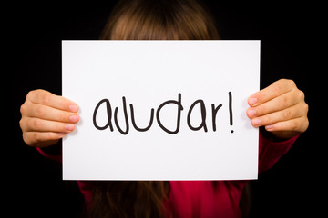 Child holding sign with Portuguese word Ajudar - Help