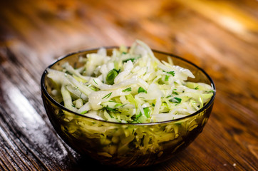 Salad with the cabbage and green onion on wooden table