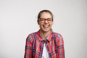 Positive human emotions. Studio portrait of relaxed carefree young woman with toothy smile wearing...
