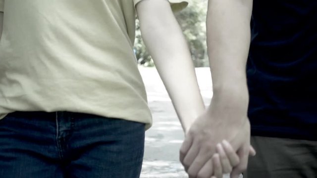 Romance male and female college students holding hands and walking