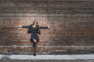 Fototapeta na wymiar Girl with long hair near an old brick wall