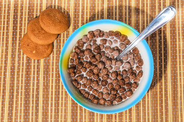 Flakes of cereals in a blue plate on a bamboo napkin