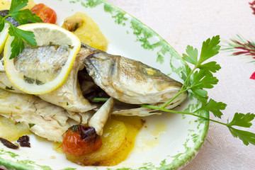 Sea bass baked with potatoes and tomatoes