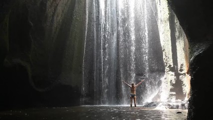 woman with raised hands in waterfall, yoga, beautiful girl practices in waterfall, body and mind harmony in the nature