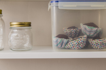 Glass pots and homemade muffins on a grey wall