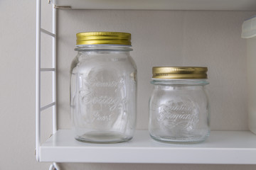 Two empty glass pots on a shelf