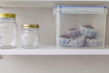 Glass pots and homemade muffins on a grey wall