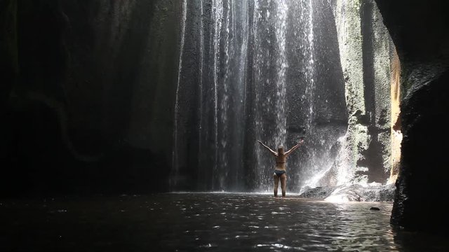 beautiful waterfall in Bali, woman in bikini bathing and swimming in the water