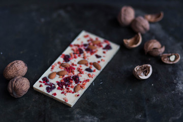 white chocolate with red berries and walnut whole nuts on black background