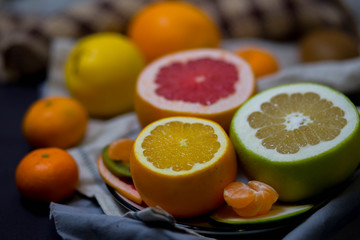 bright juicy citrus fruits in the dish and brown light beige kitchen towel in the kitchen, the festive table closeup