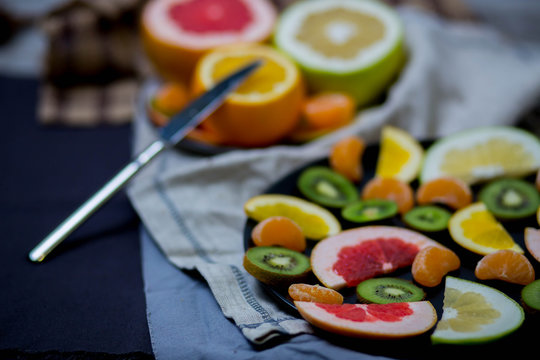 sliced pieces of citrus fruits are black two big plates of halves, blue gray, brown cloth rag towel