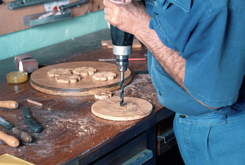 cabinet maker drilling wood with a power drill in workbench / carpenter in the workshop garage making piece of wood