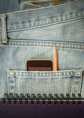 Modern phone in old blue jeans pocket.