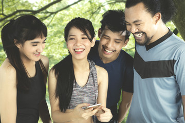 Multiracial friends with cellphone at park