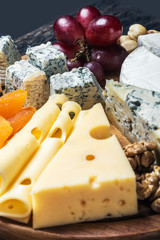 Cheese plate with fruits and nuts on a wooden table