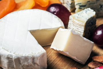 Cheese plate with fruits and nuts on a wooden table