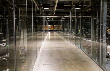 Fototapeta premium długi korytarz przemysłowy oświetlony jasnymi, białymi ścianami ze szkła podłogowego