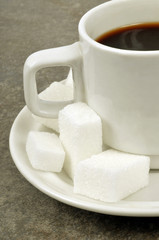 Tasse de café avec des pierres de sucre sur la soucoupe 