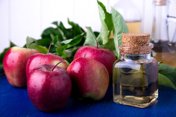 Apple cider vinegar. Three glass bottle on blue background. Red apples.