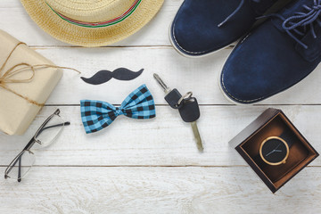 Top view Happy Father day on rustic wooden background. accessories with watch,mustache,vintage bow tie,pen,present,key car,shoes and hat.