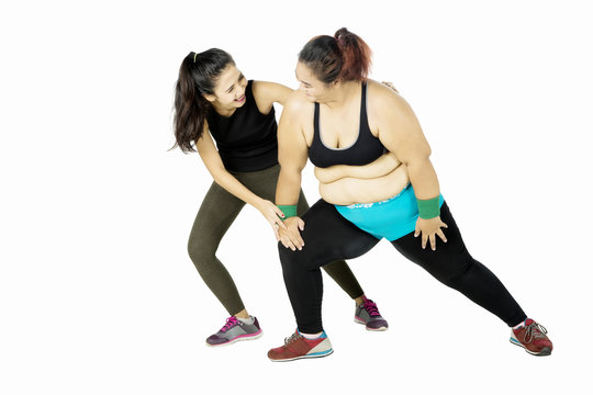Trainer helping fat woman doing workout