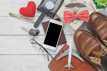 Obraz na płótnie Canvas Top view Happy Father day with travel concept.Mobile phone and passport on rustic wooden background. accessories with airplane,mustache,vintage bow tie,pen,present