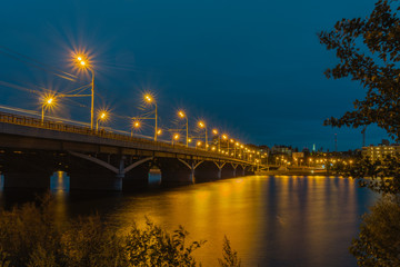 Fototapeta na wymiar Chernavsky bridge in the evening, Voronezh, Russia. An HDR image of the bridge over river and Voronezh reservoir, taken in the night.The bridge and the streetlights on it form a diagonal of the image.