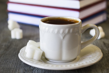 A white cup of coffee, notebooks  and pen.