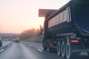 Highway with lots of cars. Truck and cars on the road under the sunset (sunrise).