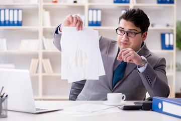 Businessman spilling coffee on important documents