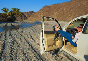 The girl behind the wheel of a car in the desert.