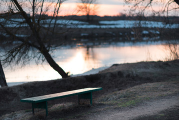 Conceptual scene on the coast of the river and a deserted bench.