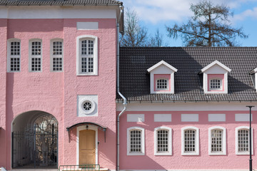 Part of facade of old building with pink cracked brick walls and semi-circular windows.