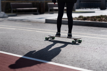 Young women is riding on a longboard in a black leggings