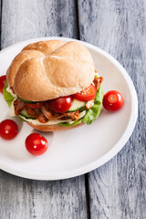 Fried chicken meat with cheese and vegetables in bun