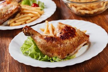 Roasted chicken legs with french fries and lettuce