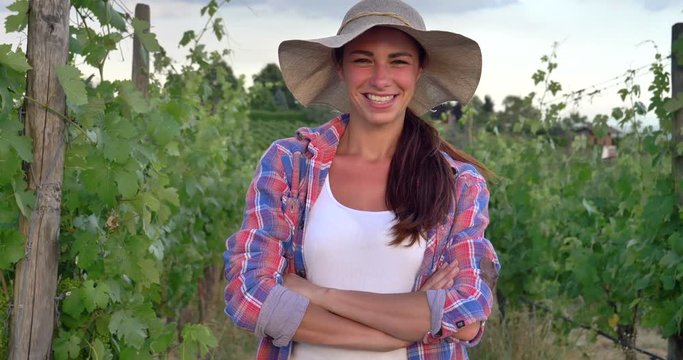 Beautiful smiling girl (woman) farmer watching over grape fields, in a straw hat and in a shirt, greens background. Concept ecology, wine, bio product, inspection, water, natural products, agriculture