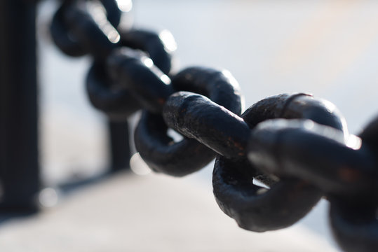 big thick steel dark metal chain links foreground closeup outside