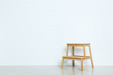 Small wooden ladder on brick wall background