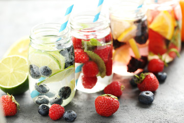 Detox water in bottles with berries on wooden table