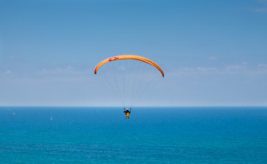 Paragliding above Mediterranean sea on blue sky background