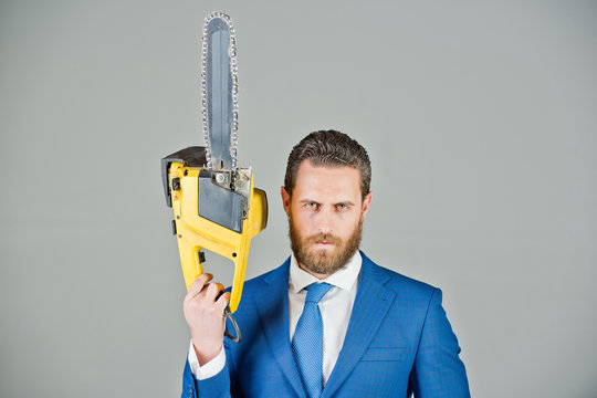 businessman or serious bearded man hold yellow chainsaw in outfit