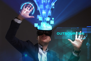 Business, Technology, Internet and network concept. Young businessman working in virtual reality glasses sees the inscription: Outsourcing