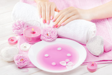 Fototapeta na wymiar beautiful pink manicure with tea rose on the white wooden table. spa